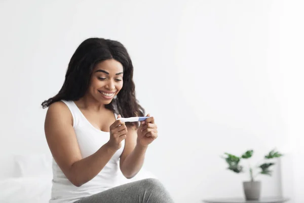La felicidad y la expectativa del niño. Feliz señora afroamericana mirando positivo prueba de embarazo — Foto de Stock