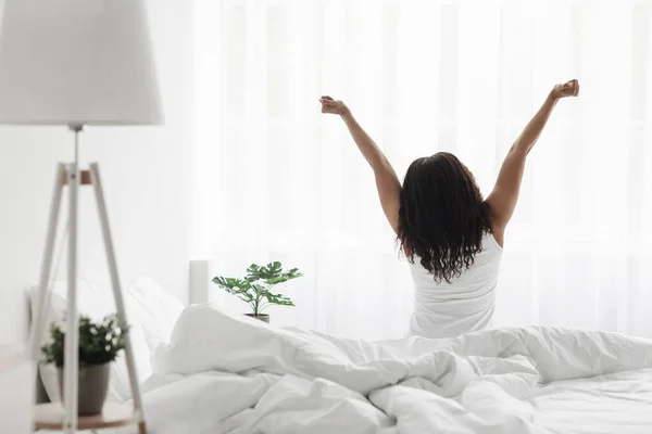 Dobré ráno. Dobře odpočatá africká americká dáma se protahuje na posteli, užívá si nový den, výhled zezadu, volný prostor — Stock fotografie