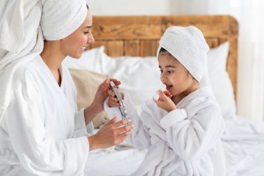 Tatlı kız aynaya bakıyor, ruj sürüyor.