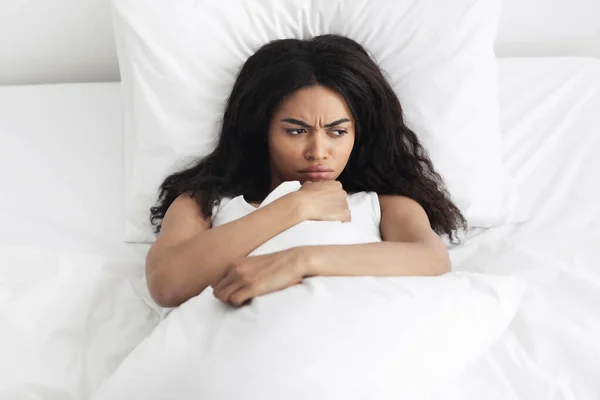 Mau conceito de sono matinal. Mulher afro-americana perturbada acordando e deitada na cama, sentindo raiva — Fotografia de Stock