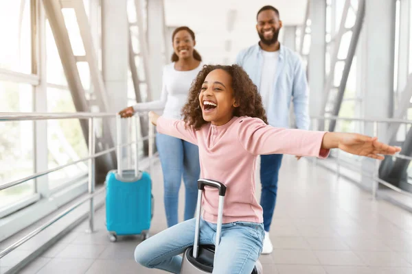 Feliz familia negra viajando con su hija, divirtiéndose en el aeropuerto — Foto de Stock