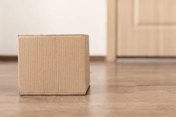 Entregado caixa de papelão deitado no chão perto da porta do apartamento — Fotografia de Stock