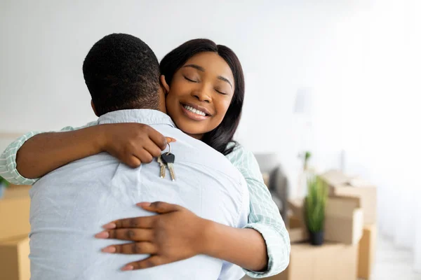 House ownership concept. Excited black woman holding house key and hugging her husband, free space — Stock Photo, Image