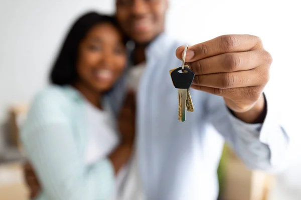 Novos donos de casa. Feliz casal afro-americano segurando as chaves de casa, celebrando a compra de novo apartamento, foco seletivo — Fotografia de Stock