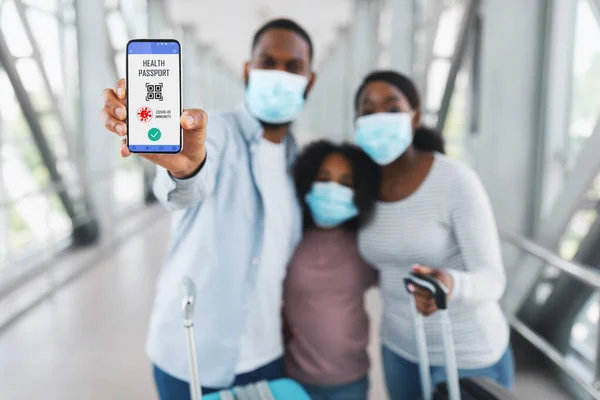 Turistas negros mostrando smartphone con pasaporte digital Immune para covid-19 —  Fotos de Stock