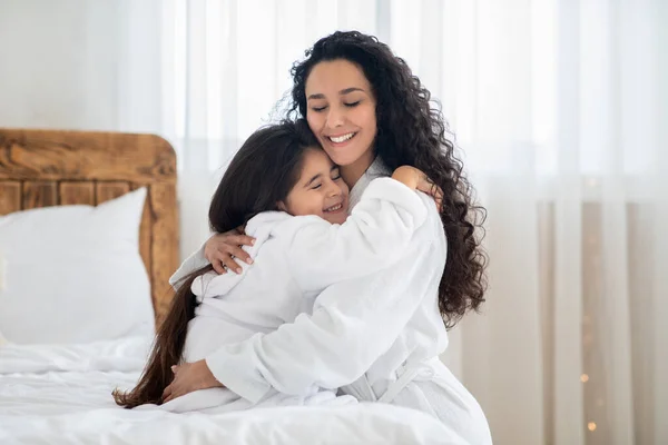 Madre e hija cariñosas en albornoces abrazando —  Fotos de Stock