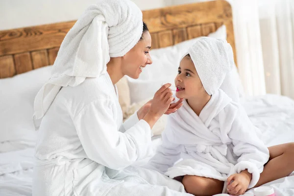 Mamá poniendo maquillaje en su pequeña hija linda —  Fotos de Stock