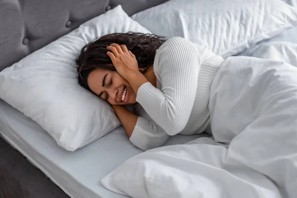 Donna nera che piange, sdraiata sul letto che copre il viso — Foto Stock