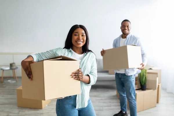 Glückliches afrikanisch-amerikanisches Paar zieht um, hält Papierboxen in der Hand und packt sie nach dem Umzug in eine eigene Unterkunft aus — Stockfoto