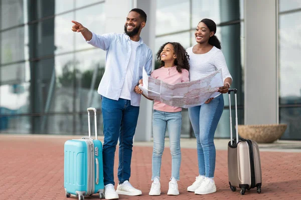 Szczęśliwa czarna rodzina podróżująca z dzieckiem, trzymająca mapę — Zdjęcie stockowe