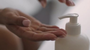 Vücuda karşılık cilt bakımı. Kırbaçlanmış zenci kadın evdeki nemlendirici losyonu alıp ellerine sürüyor.
