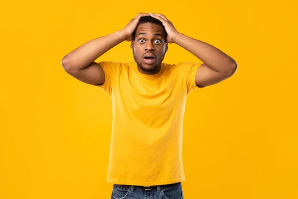 Zwarte man aanraken hoofd in shock poseren over gele achtergrond — Stockfoto