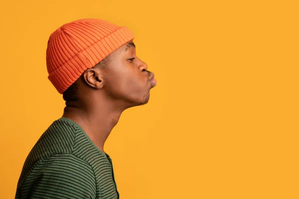 Perfil retrato de jovem preto cara em laranja chapéu enviando beijo de ar — Fotografia de Stock