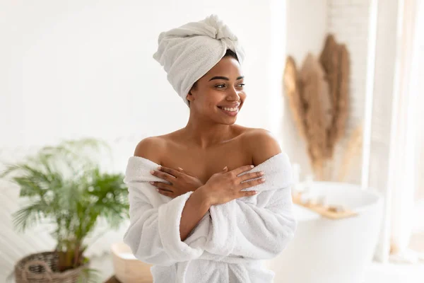 Atractiva mujer afroamericana posando usando albornoz blanco en el baño — Foto de Stock