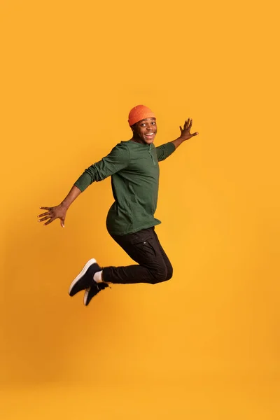 快乐的黑人年轻人在黄色背景下空中跳跃的画像 — 图库照片