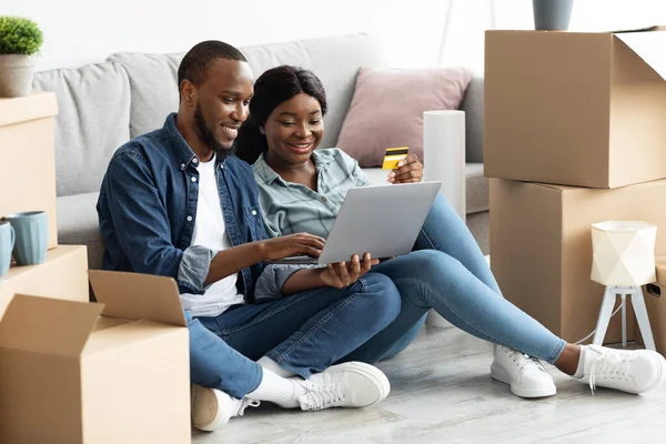 Negro casado pareja de compras en línea con el ordenador portátil y tarjeta de crédito después de mudarse — Foto de Stock