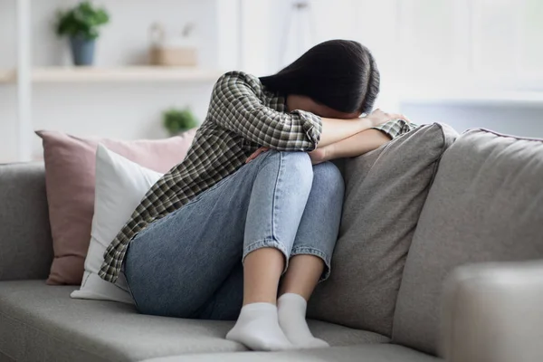 Aufgebrachte junge Frau sitzt auf Couch und weint — Stockfoto