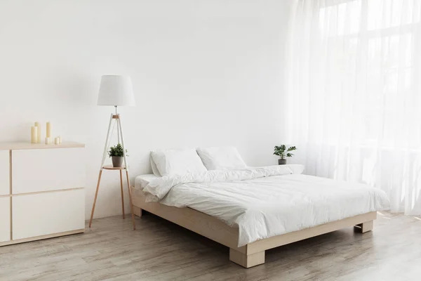 Design moderno simples, anúncio, oferta. Cama de casal com almofadas brancas e cobertor macio, lâmpada, móveis no chão de madeira — Fotografia de Stock