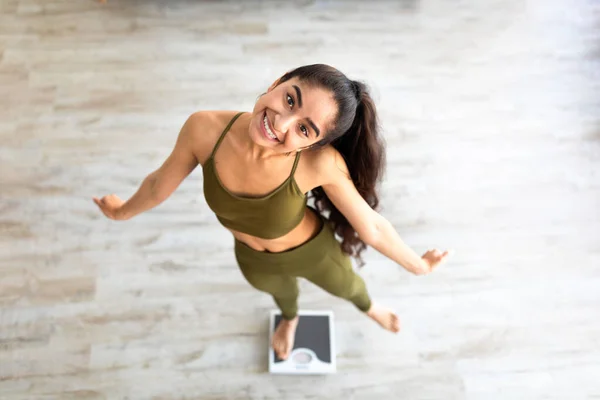 Über der Ansicht der Millennial Indian Lady, die auf Waagen tanzt und einen gesunden Lebensstil wählt, glücklich mit dem Schlankheitsergebnis — Stockfoto