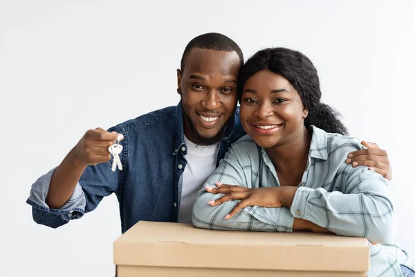 Переезд. Портрет счастливых чёрных супругов, позирующих с ключами и картонной коробкой — стоковое фото