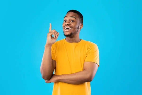 Schwarzer Mann zeigt mit erhobenem Finger auf Idee über blauen Hintergrund — Stockfoto
