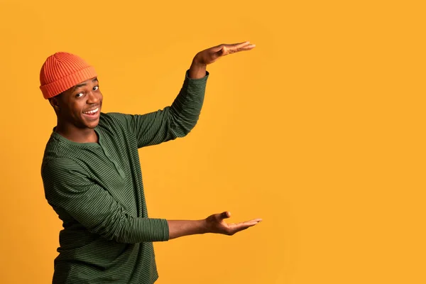 Pozitif Siyah Adam Sarı Arkaplan Üzerinde Büyük Görünmez Nesne Tutuyor — Stok fotoğraf