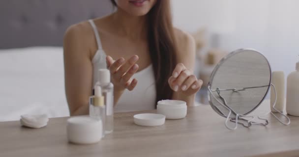 Close-up shot van jonge onherkenbare dame aanbrengen hydraterende crème op haar handen huid, zitten in de slaapkamer — Stockvideo