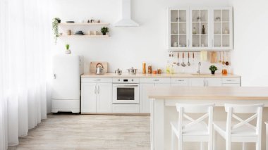 Aile yemek odası ve minimalist mutfak. Ahşap masa, beyaz sandalyeler, mutfak gereçleri ve mobilyalar.