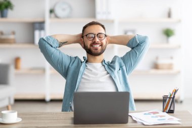 Gülümseyen beyaz iş adamı ev bilgisayarının önünde dinleniyor, online işe ara veriyor.