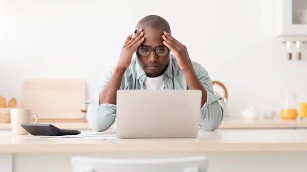 Drága modern élet. Csalódott érett afro-amerikai férfi kiszámítása adók vagy tervezési költségvetés, ül a konyhában — Stock Fotó