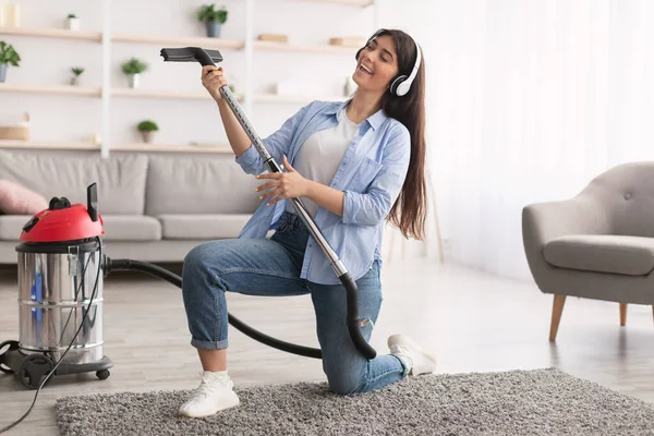 Kobieta sprzątanie domu, śpiew i używanie odkurzacza jako gitary — Zdjęcie stockowe