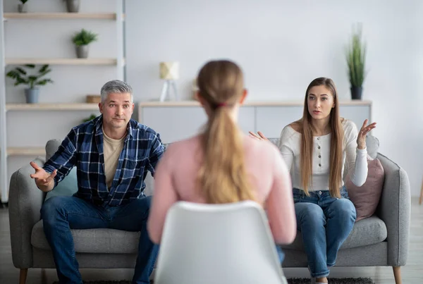 Mature couple having argument at psychologists office, matiral counselor sitting with back to camera — Stock Photo, Image