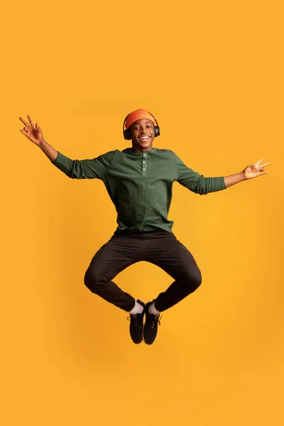 Портрет щасливого чорного хлопця в бездротових навушниках Стрибки в повітрі — стокове фото