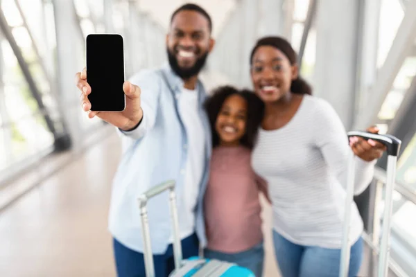 Familia negra mostrando la pantalla vacía en blanco del teléfono inteligente en el aeropuerto — Foto de Stock