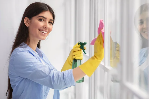 집안에서 헝겊 과 세척제 스프레이로 창을 닦고 있는 여자 — 스톡 사진