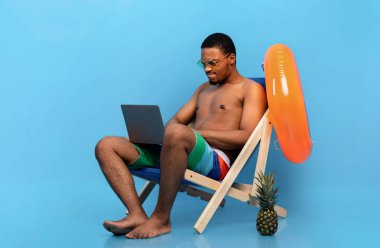 Bilgisayar sorunları. Hüsrana uğramış siyahi adam yaz tatilinde şezlongda otururken dizüstü bilgisayarla sorun yaşıyor.