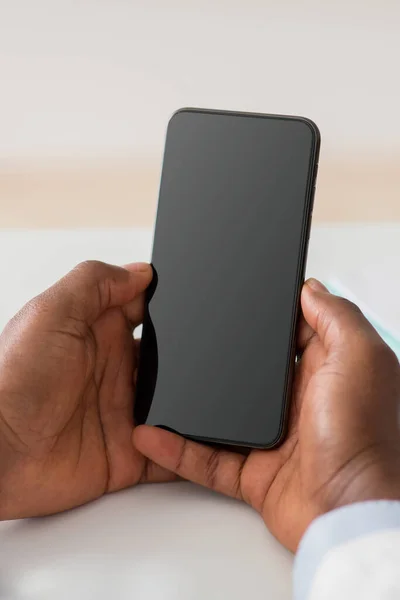 Afrikansk amerikansk läkare håller smartphone med tom skärm, ledigt utrymme, mockup, närbild — Stockfoto
