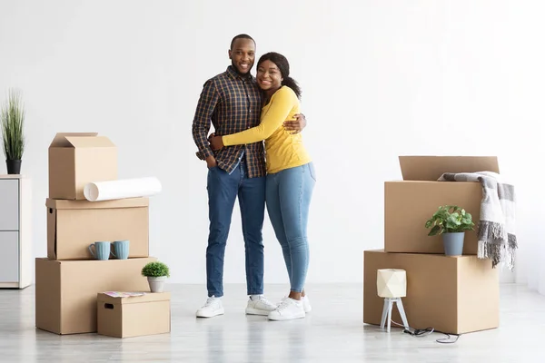 Portret van gelukkige Afro-Amerikaanse echtgenoten staand tussen kartonnen dozen na het verplaatsen — Stockfoto