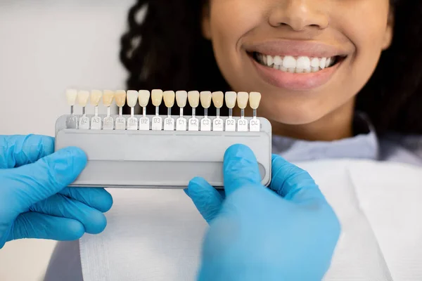 Estomatólogo sosteniendo dientes dentales sombra carta guía elección de color para el paciente femenino — Foto de Stock