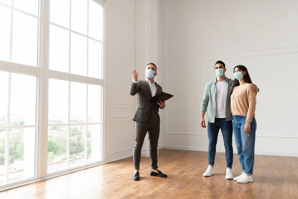 Estate Agent In Medical Mask Showing Buyers New Apartment — 图库照片