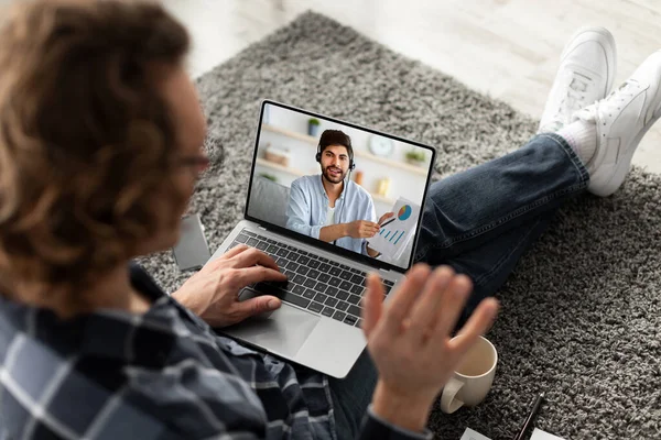 Young guy taking online business class, communicating to his tutor on web, waving at camera, indoors. Remote education — Stock Photo, Image