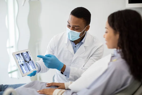 Μαύρος οδοντίατρος που δείχνει το αποτέλεσμα της θεραπείας στην ψηφιακή ταμπλέτα για τη γυναίκα ασθενή — Φωτογραφία Αρχείου