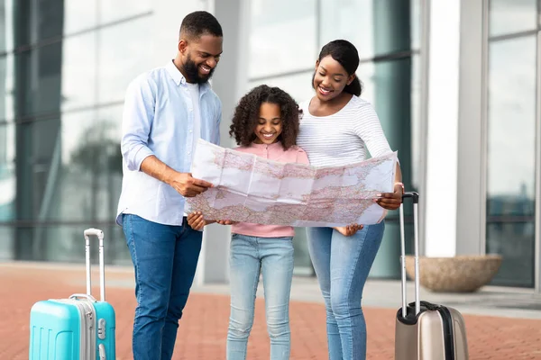 Щаслива чорна сім'я, що подорожує з дитиною, тримає карту паперу — стокове фото