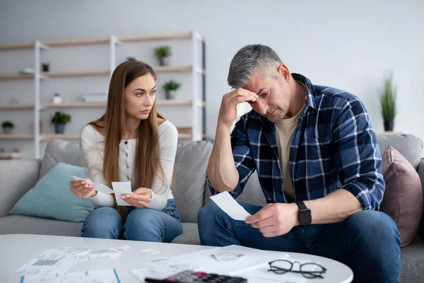 Serious mature man and his wife calculating family budget or taxes, checking bills and expenses, having debts at home — Stockfoto