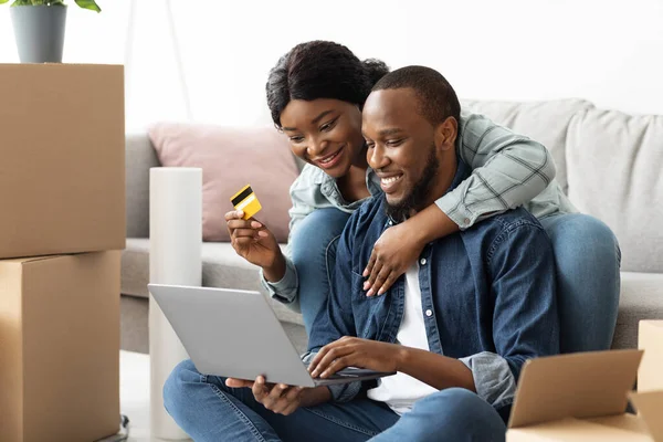 Online Shopping. Cheerful Black Spouses With Laptop Choosing Furniture After Moving Home — Stock Photo, Image