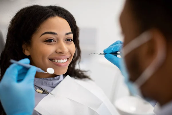 Красива усміхнена чорна жінка сидить на стоматологічному стільці готовий для перевірки — стокове фото
