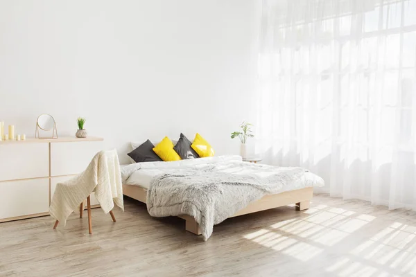 Quarto acolhedor e feminino com travesseiros e plantas na parede branca em branco — Fotografia de Stock