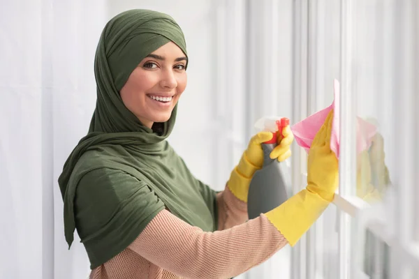 Finestra di pulizia donna musulmana con straccio e spray detergente — Foto Stock