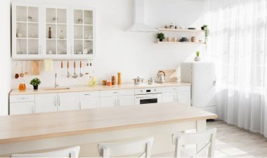 Light kitchen design with white wooden furniture and island, utensils and kitchenware on shelves, range hood