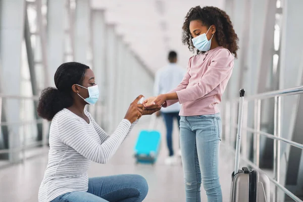 Black woman traveling with kid, using sanitizer — 스톡 사진
